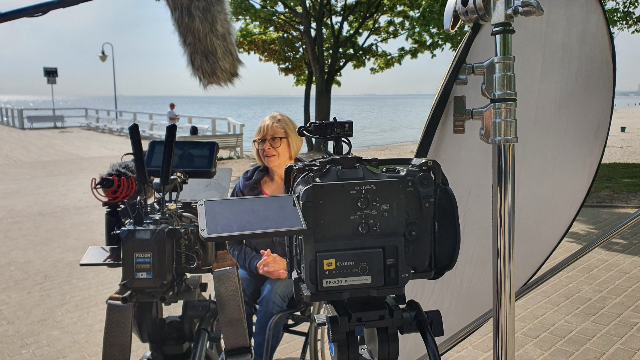 A fixed-scope interview setup: the subject framed between two cinema cameras and a reflector.