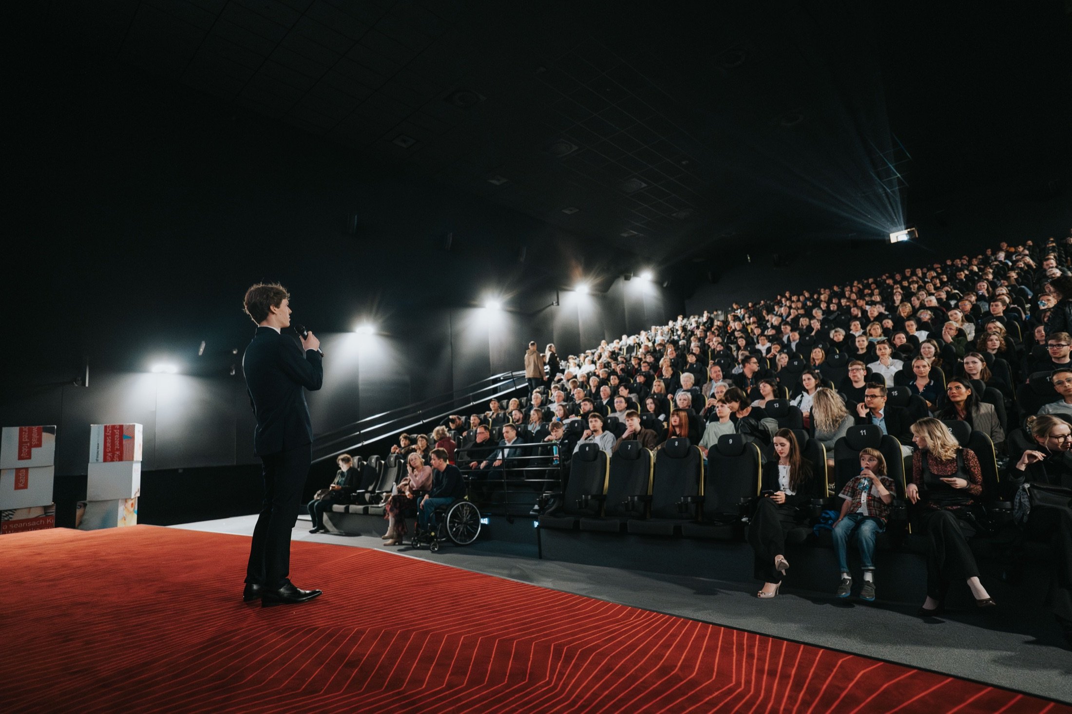 A full cinema house on the Tena lavitra screening tour, host on the red-lit stage.