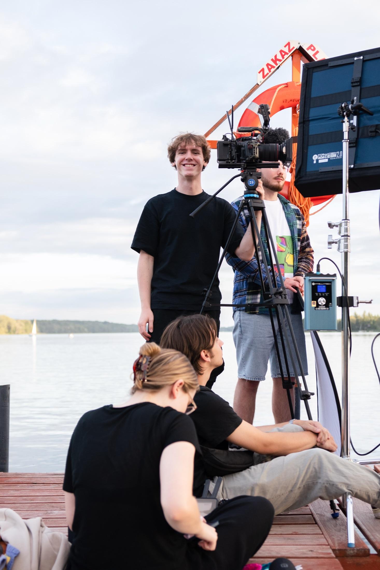 Crew beim Aufbau eines Kamera-Jib-Arms an einem See während eines Außendrehs.
